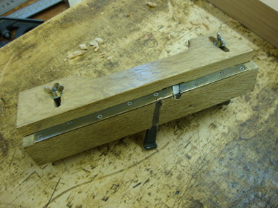 Underside of a rabbet plane showing the adjustable fence.